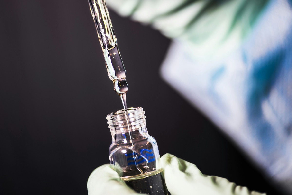 Pipeta dosificando líquido gota a gota dentro de un vial de laboratorio