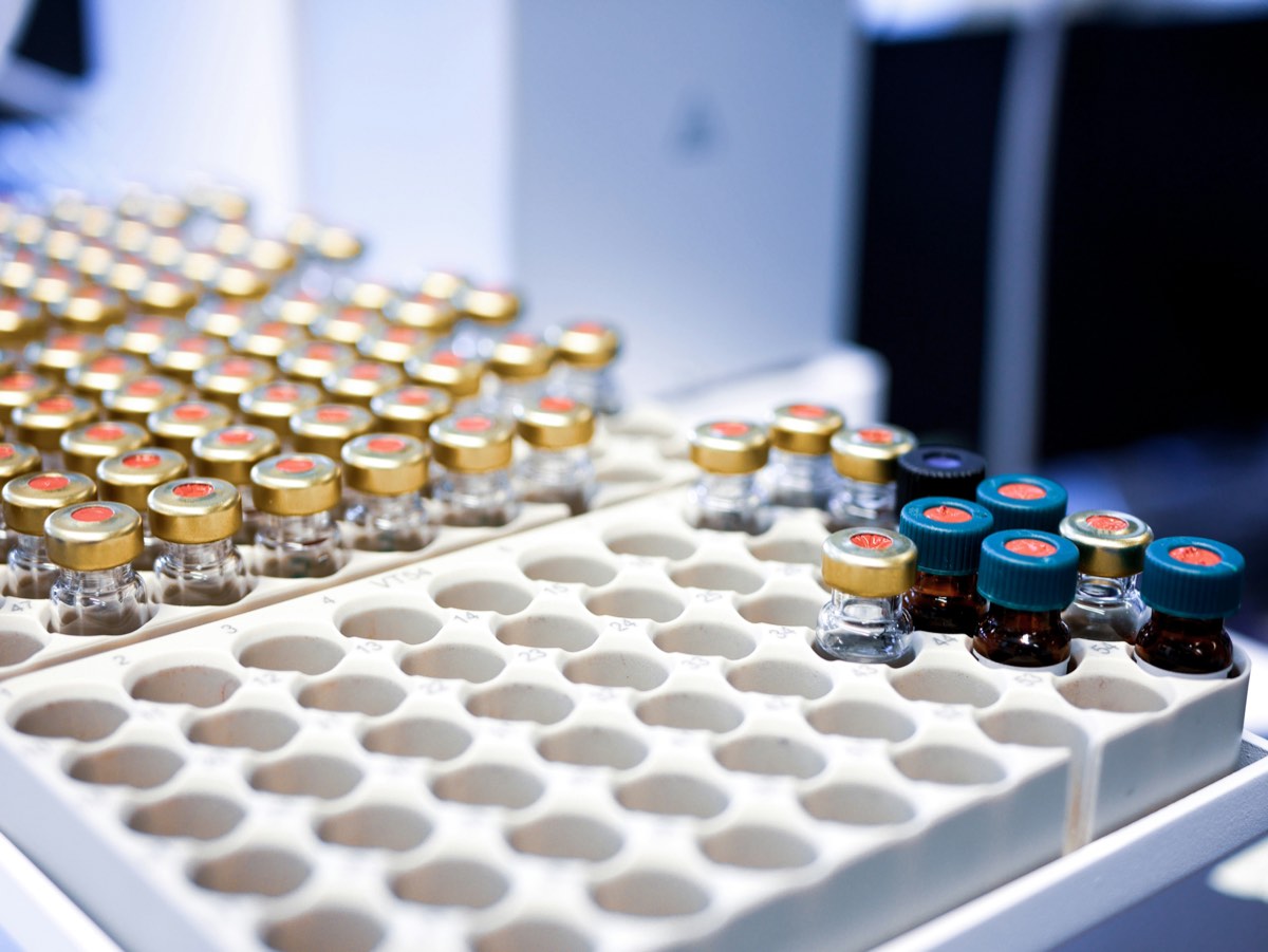 Viales de vidrio con distintos tapones ordenados en una bandeja de almacenamiento de laboratorio